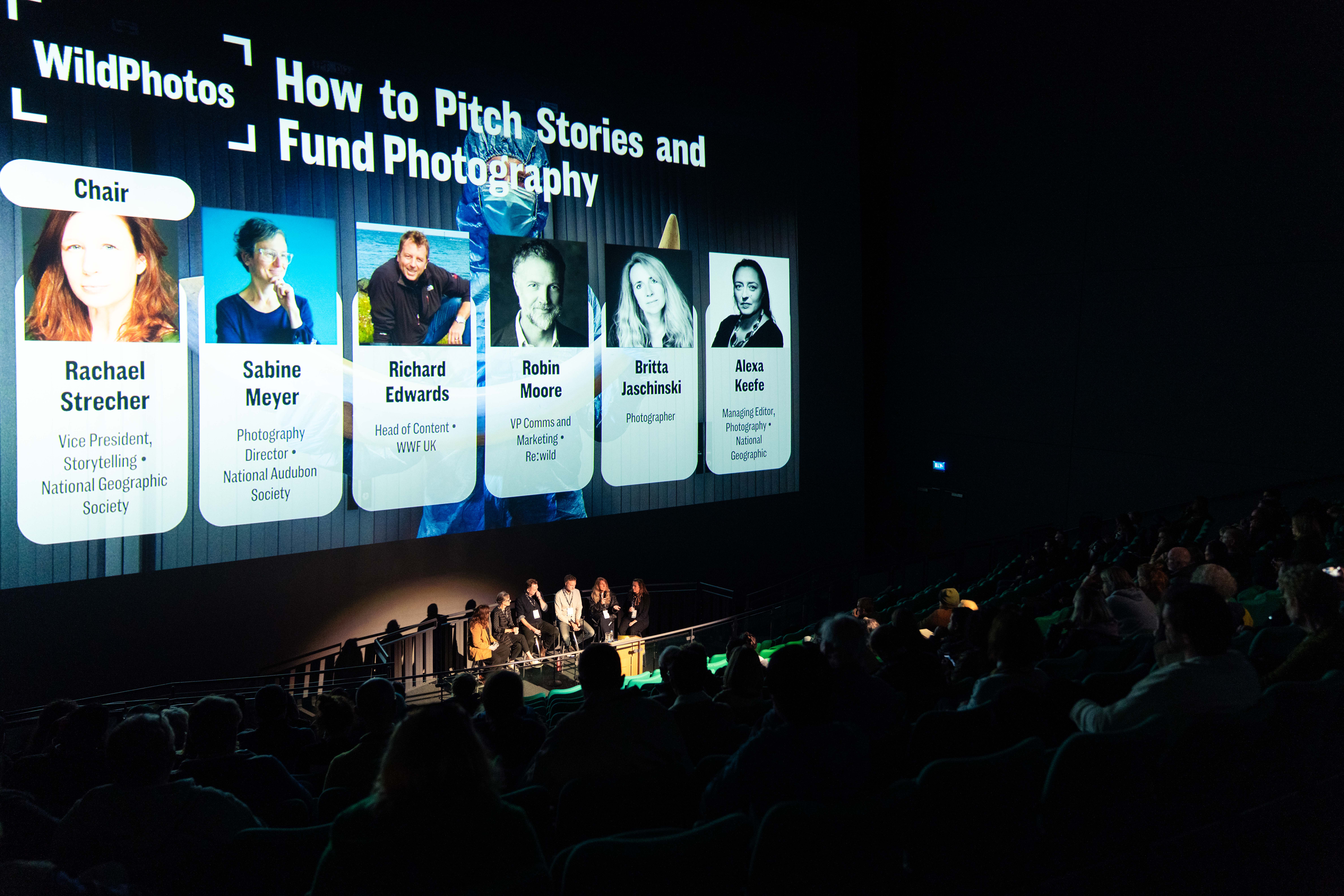 WildPhotos event with speakers and a large screen behind them
