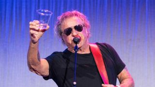 Sammy Hagar onstage, raising a drink in salute