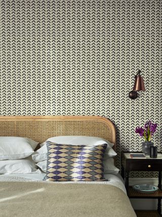 country bedroom with wallpaper and woven bedhead