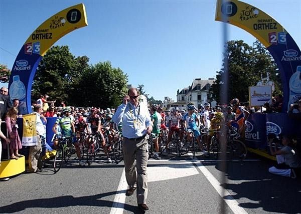 Race director Christian Prudhomme stands in front of the peloton before stage 16