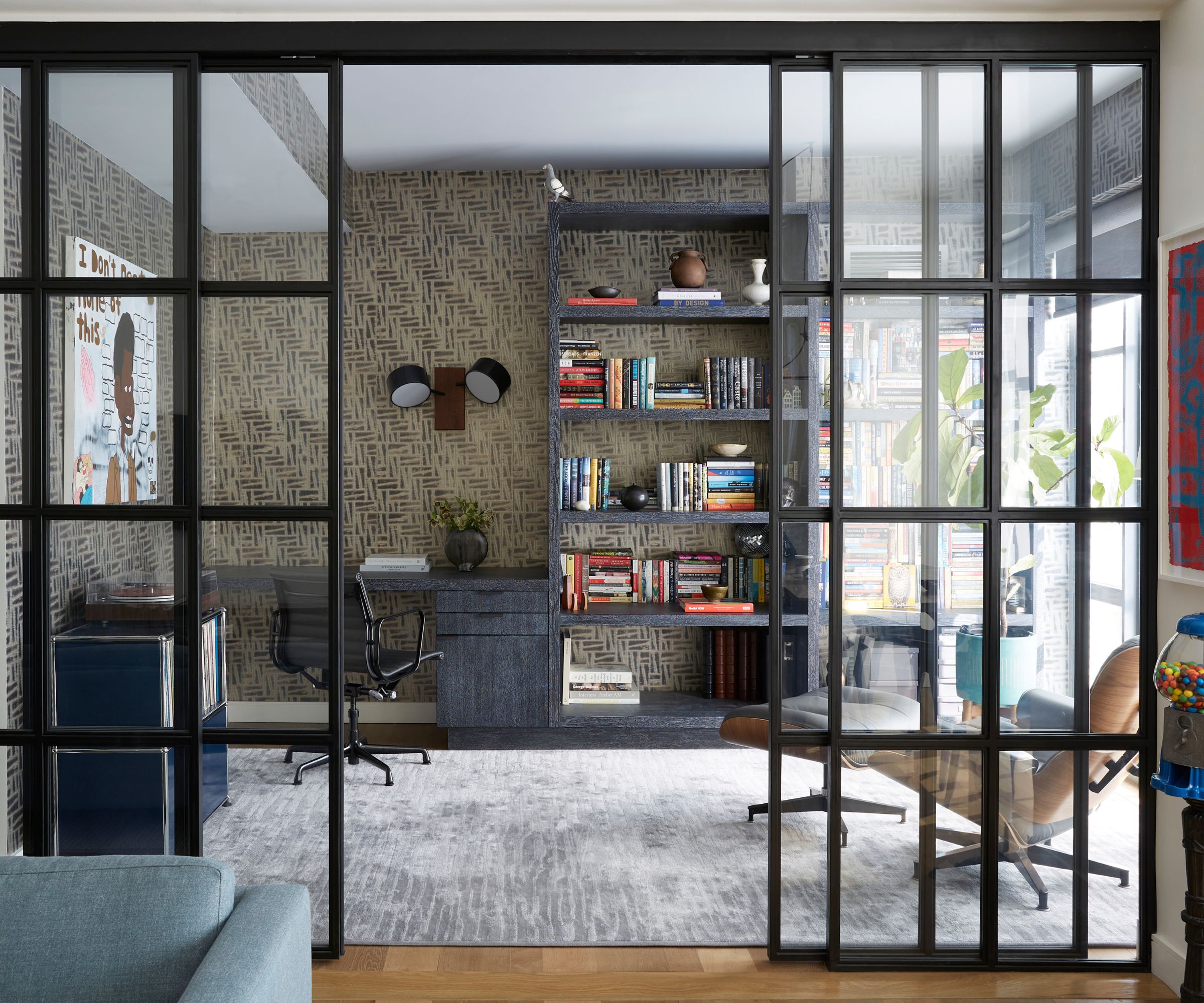 View of home office with shelving and desk behind glass panel walls in living space