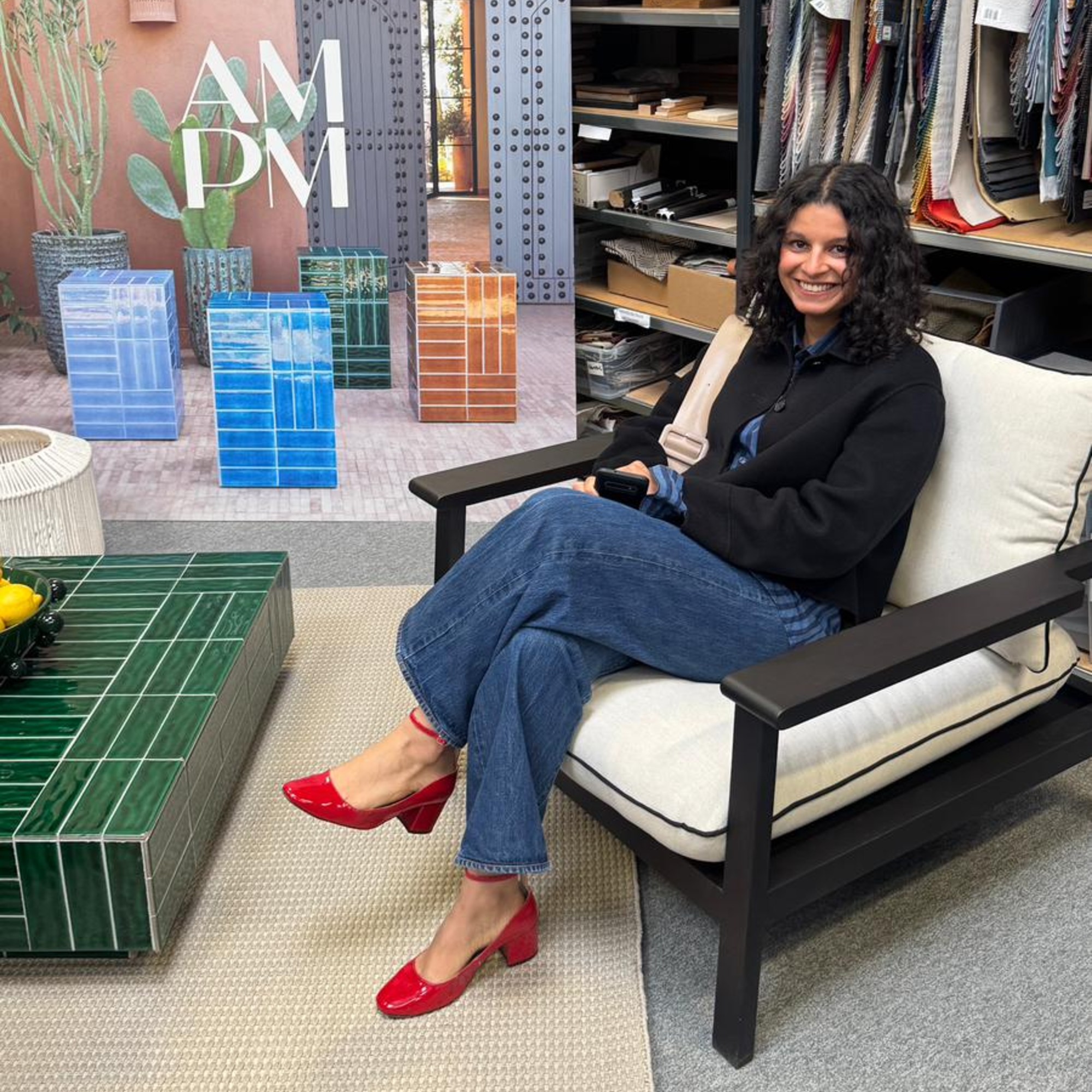 Sara sitting on a garden chair from La Redoute's AM.PM brand with a green tiled garden coffee table