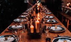 A long table decorated with plates, glasses and candles