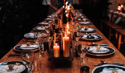 A long table decorated with plates, glasses and candles