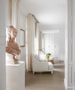 White bedroom with wooden floor and terracotta sculpture in Edwardian house in West London designed by Philip Vergeylen of Nicholas Haslam
