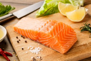 A raw salmon steak on a wooden board