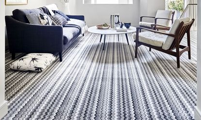 Striped white and navy carpet in lounge with wooden seating and glass topped coffee tabel