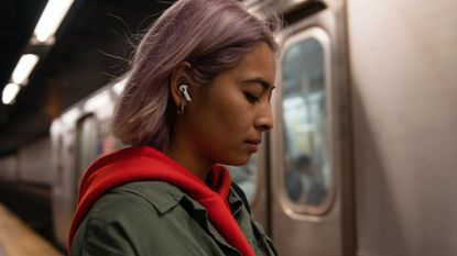 Apple AirPods Pro wireless earbuds being worn by a woman in a subway station