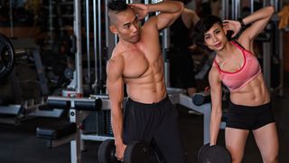Photo of a man and woman performing side bends with dumbbells
