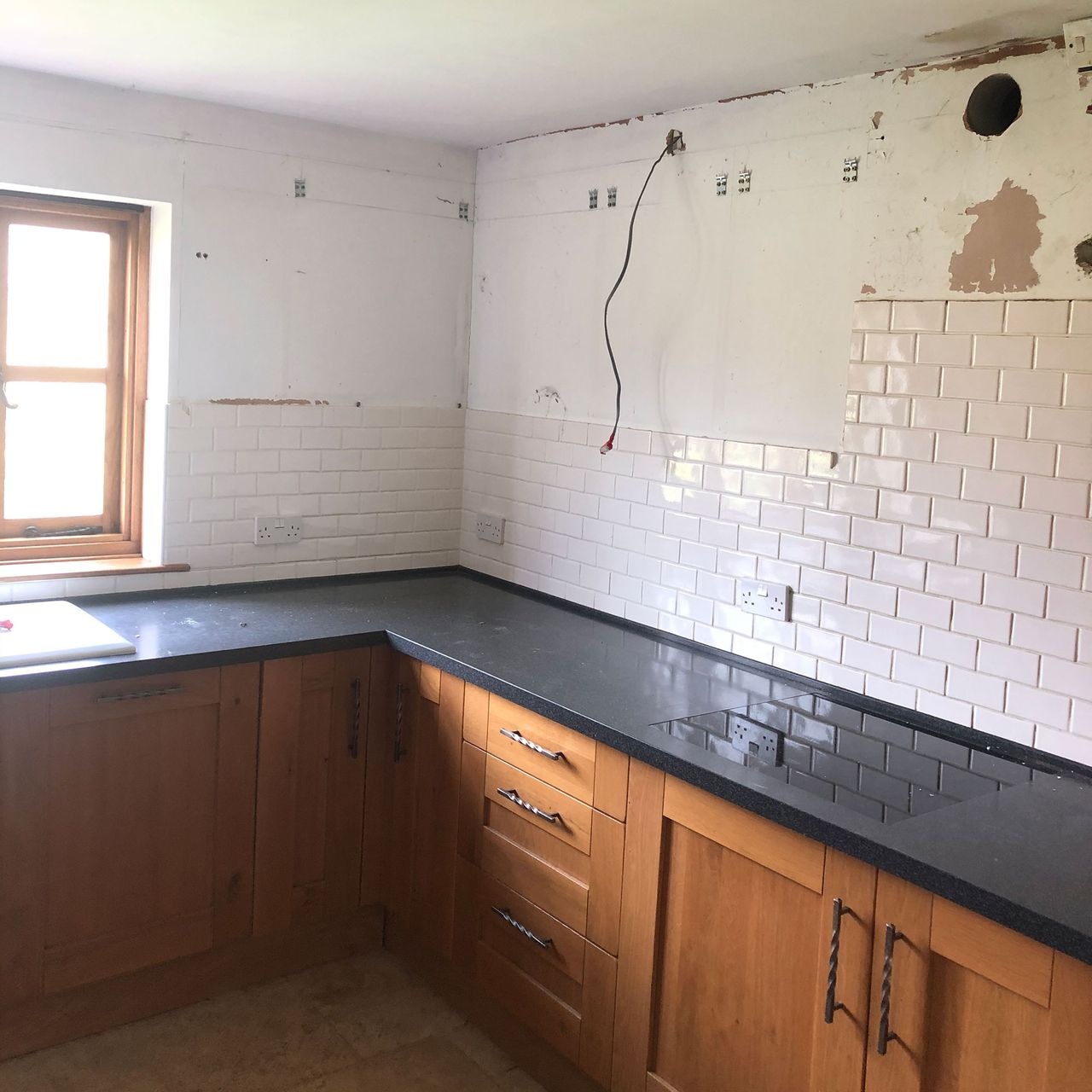 Wooden kitchen with upper cabinets ripped out and white walls