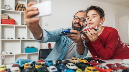 A father and his young son look over their collection of toy cars.