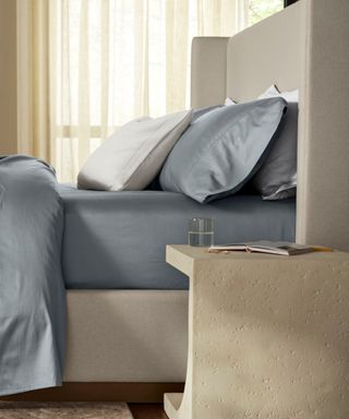 Side view of blue and white bedding on a gray bed frame against a granite-effect nightstand.