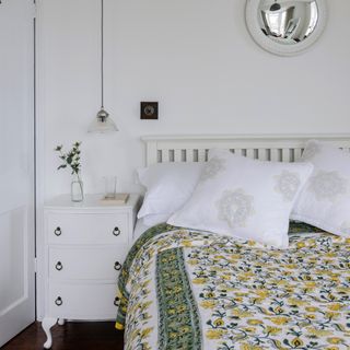 White bedroom with double bed, floral duvet and pendant light