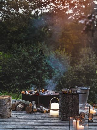A fire pit with burning logs on a deck on a summer's evening