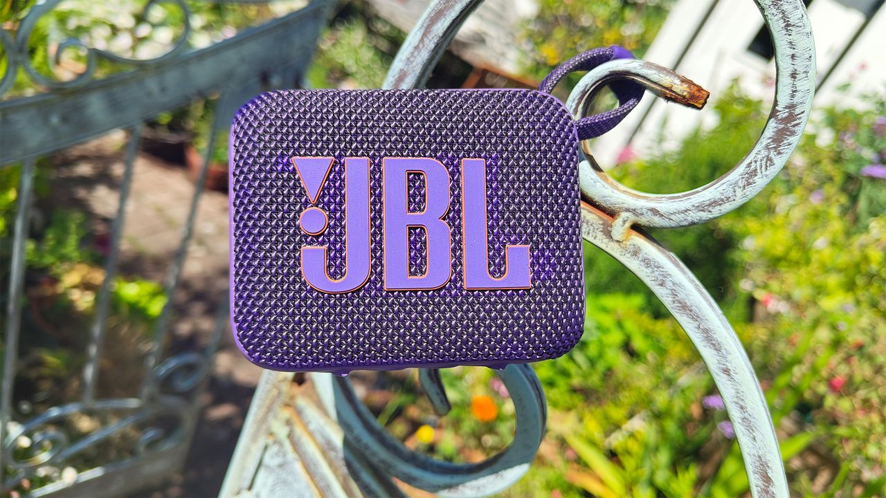 JBL Go 4 Bluetooth speaker in purple on a gate