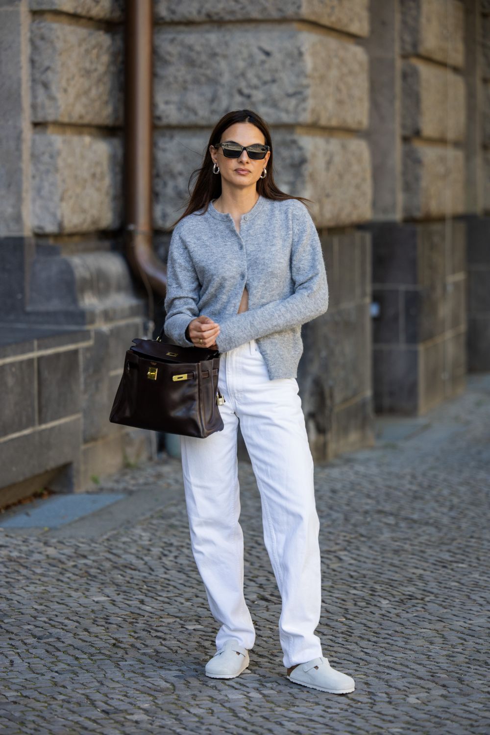 a woman wearing white jeans and a cashmere cardigan