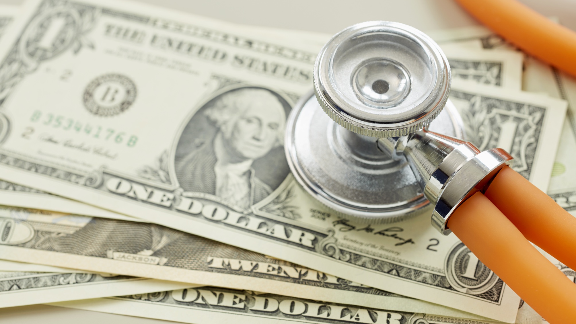 A stethoscope on top of dollar bills.