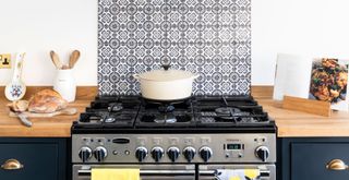 White kitchen walls with a blue patterned tiled splash back behind a range cooker to demonstrate how to make a kitchen look expensive on a budget with a DIY tile protect