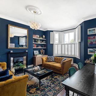 Blue living room with green sofas, patterned rug and mirror on the wall