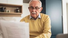 Senior man focusing on paperwork at home