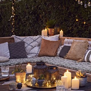 garden area with cushions on bench and coffee table with candles