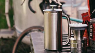 The ESPRO French press coffee maker in stainless steel with a bike in the background