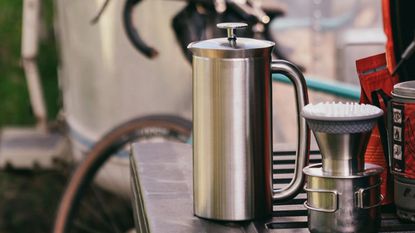 One of the best French presses, the ESPRO French press coffee maker in stainless steel with a bike in the background
