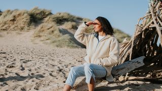 woman sitting on the beach wearing a jumper