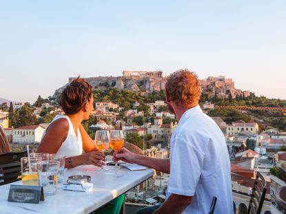 Couple drinking in front of Athens' Acropolis at sunset