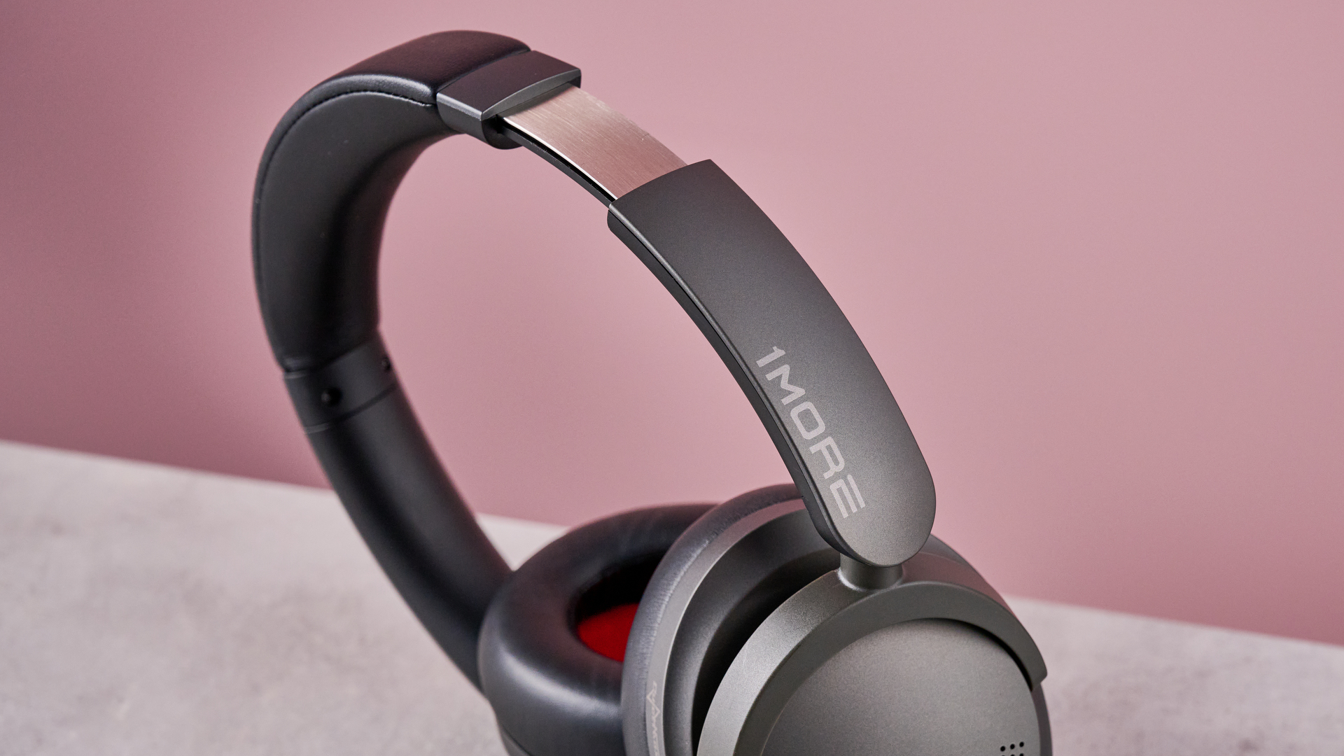 1More SonoFlow Pro HQ51 headphones on a gray surface with a pink background, showing the logo on the headband