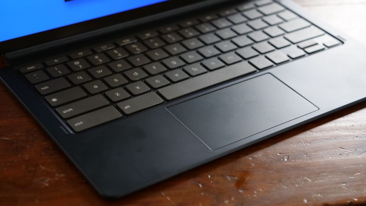 A close up of a laptop keyboard against a wooden surface