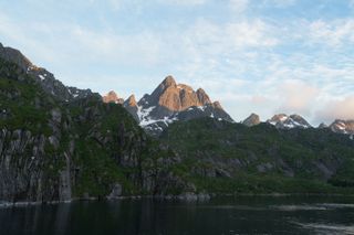 the sun rises on a rocky mountain overlooking the sea