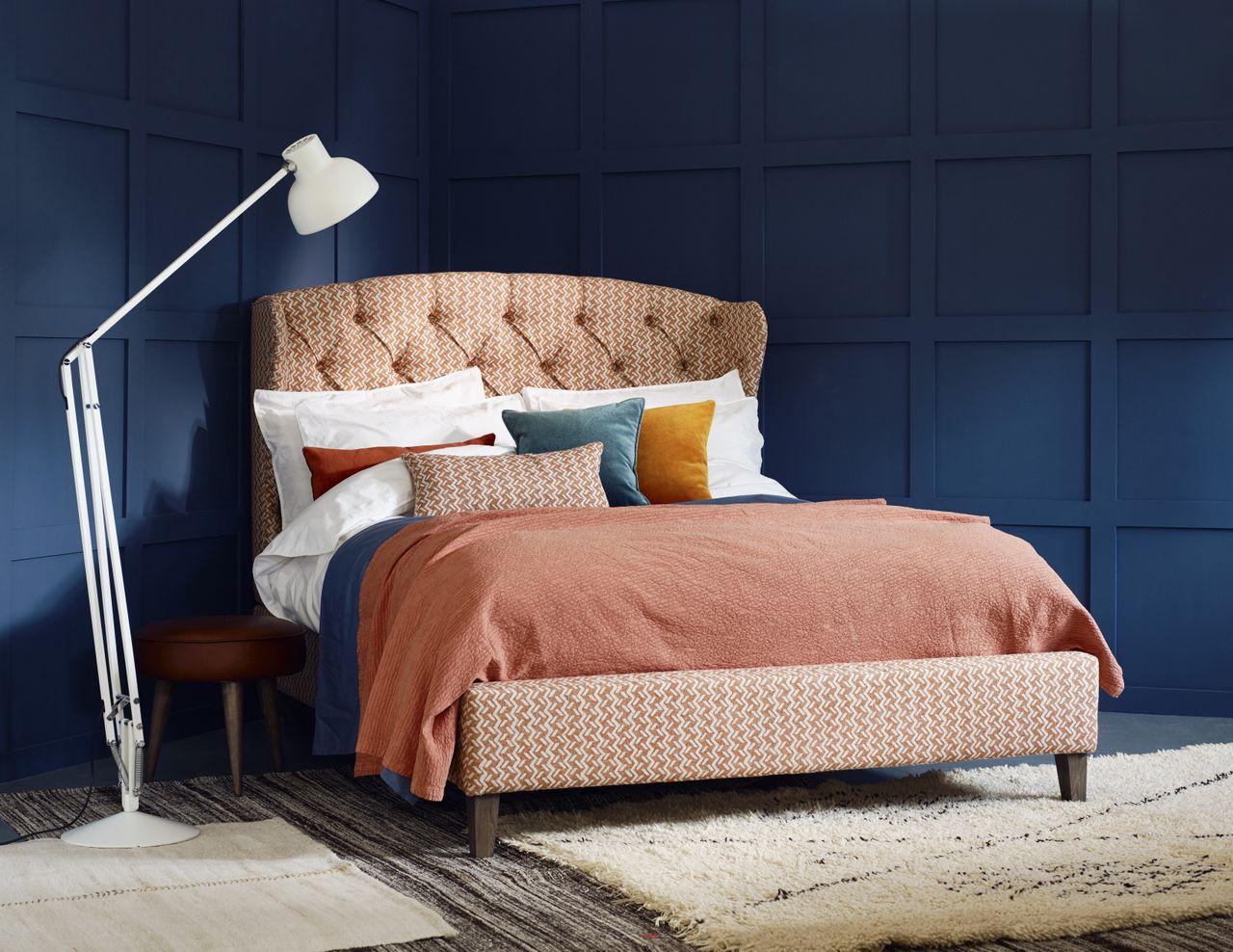 high backed bed with fabric headboard and blue walls