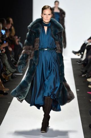 Model wearing fur coat, walking on catwalk