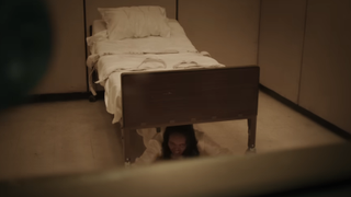 A possessed girl hiding under the bed in The Exorcist: Believer.