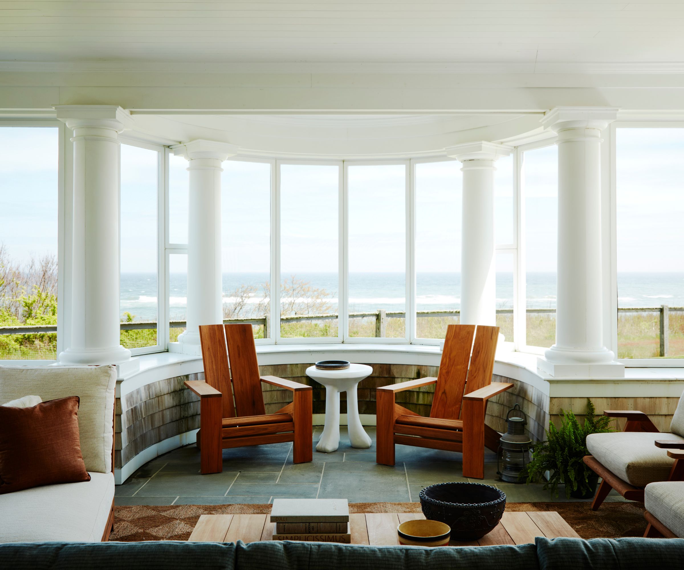 Front porch with columns, wood chairs, coffee table and sofa looking out onto seat