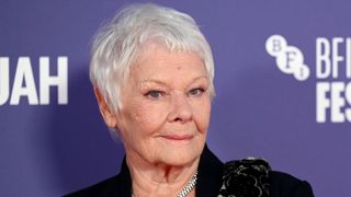 Judi Dench smiling with a silver pixie cut and wearing a black velour blazer