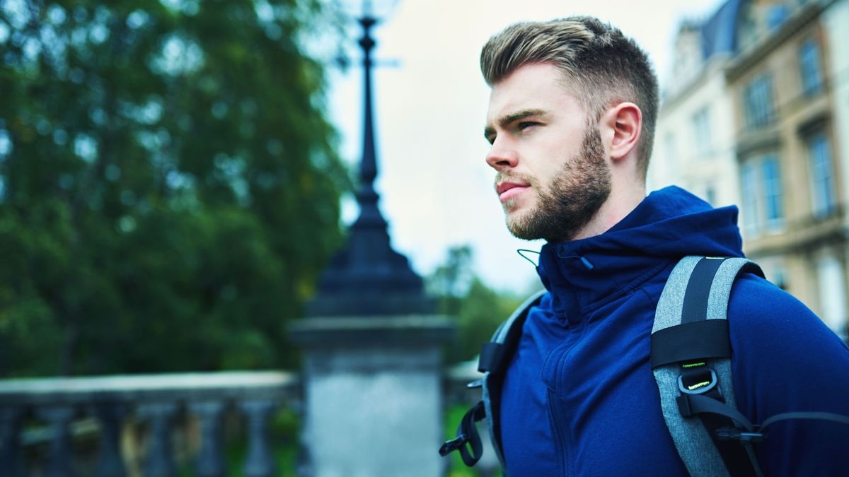 Man wearing running jacket and backpack in city