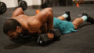 Zack George performing a burpee holding dumbbells