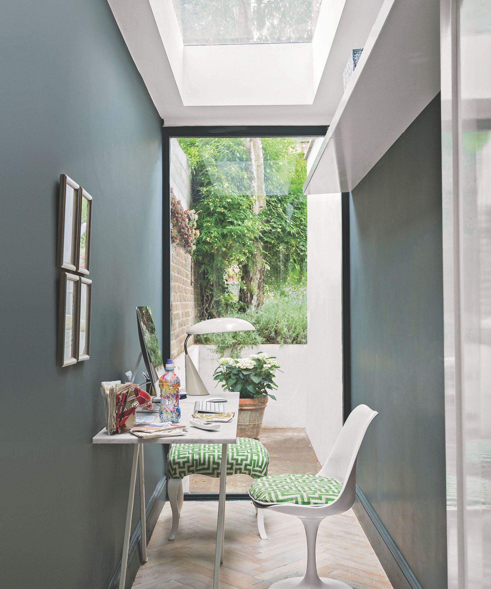 Narrow home office with skylight and white table and chairs