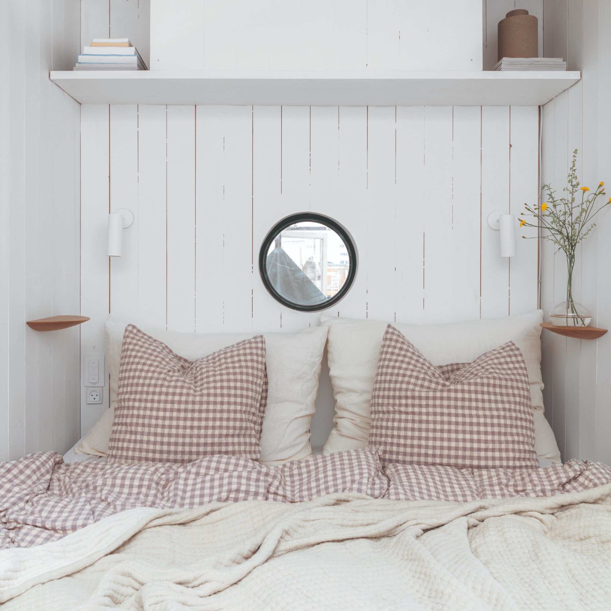 A small box bedroom room perfectly fitting a bed with gingham bed linen and white wall panelling