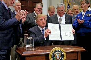U.S. President Donald Trump holds up 'Space Policy Directive 1' after signing it during a ceremony with NASA astronauts (R-L) Peggy Whitson, Buzz Aldrin and Jack Schmitt in the Roosevelt Room at the White House December 11, 2017 in Washington, DC. On the 45th anniversary of Apollo 17 -- the last crewed mission to the moon -- Trump signed the order directing NASA 'to lead an innovative space exploration program to send American astronauts back to the Moon, and eventually Mars,' according White House spokesman Hogan Gidley.