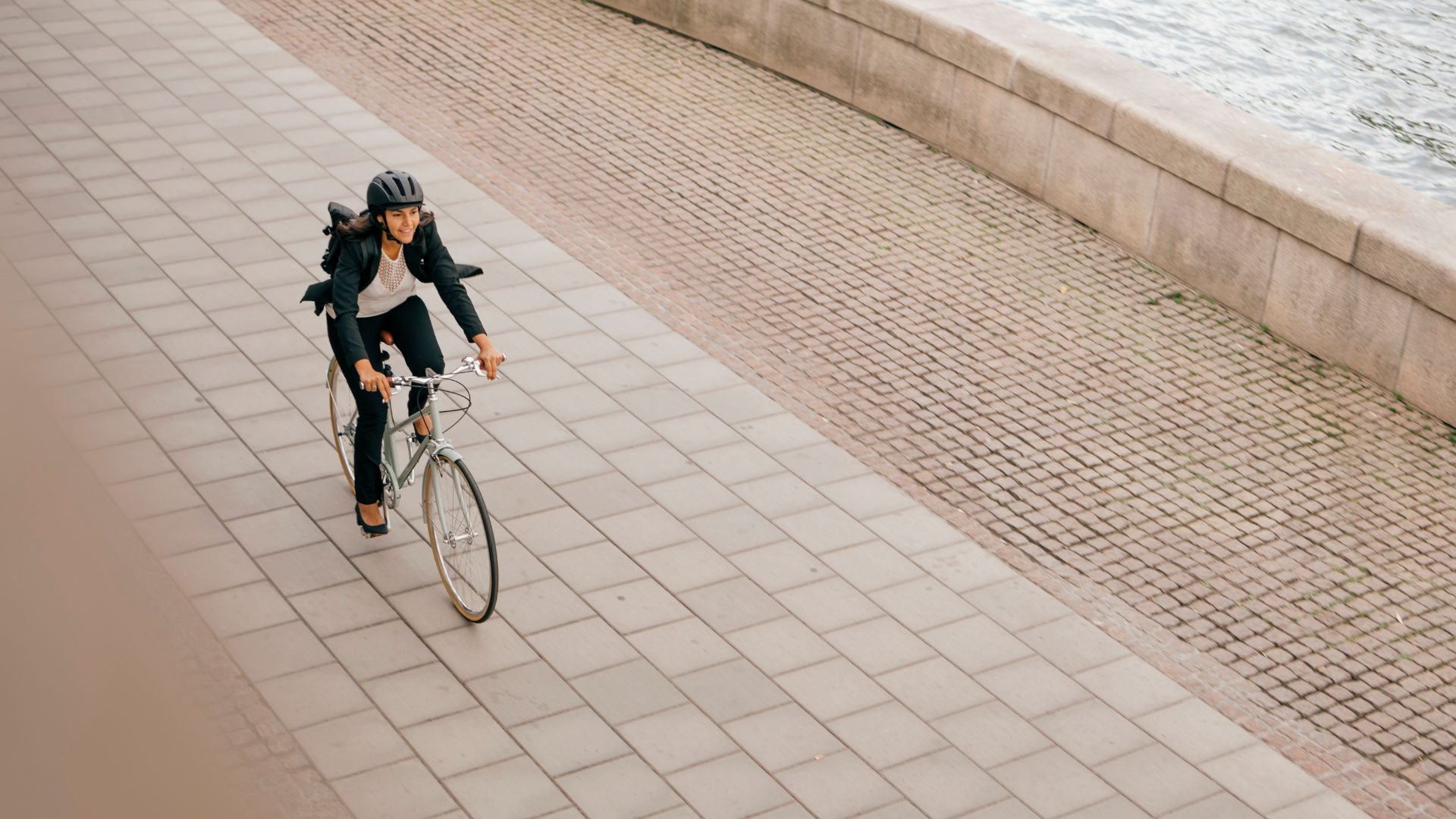 Woman riding a bike along path wearing a suit