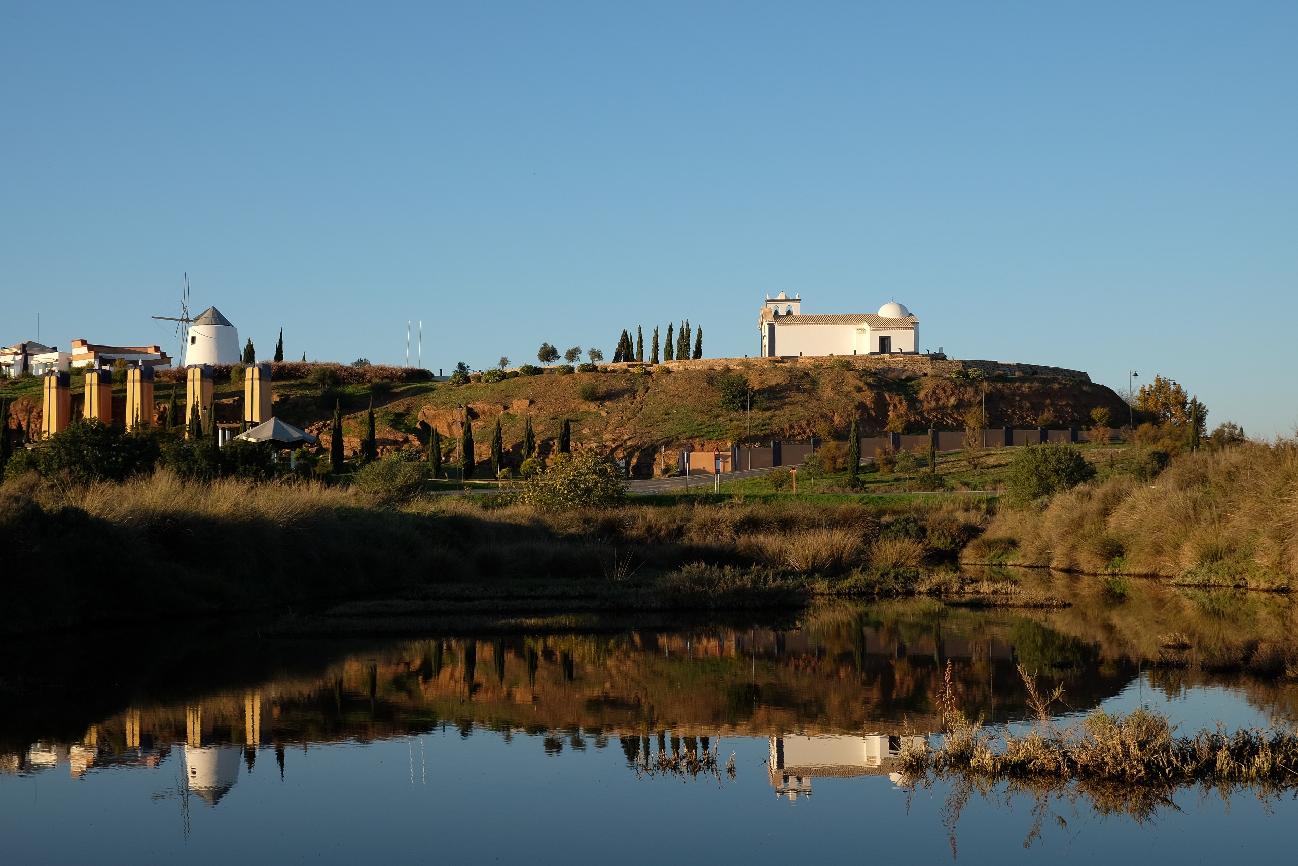 A body of water with a church and windmill in the background