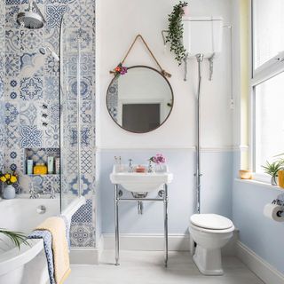bathroom with white and blue wall wash basin commode and mirror on wall