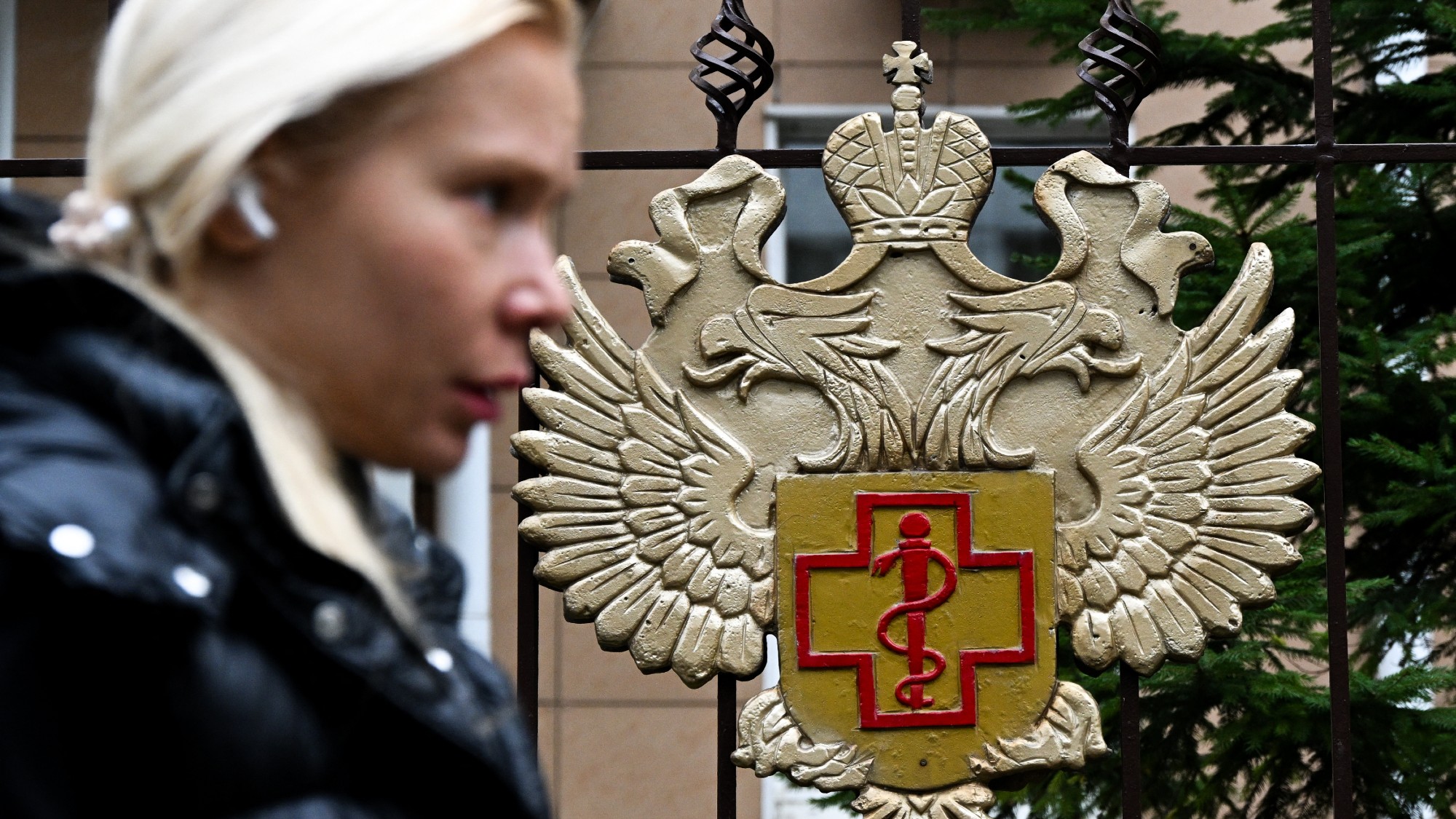A woman walks past the logo of Russia&rsquo;s consumer and health watchdog Rospotrebnadzor sitting on its grounds' fencing in Moscow
