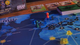 Pandemic board, cards, and tokens on a wooden table