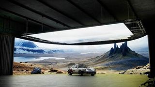 A vintage Porsche parked in a studio with a massive LED screen displaying a scenic mountain landscape