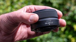 Nikon Z DX 24mm f/1.7 camera lens held in a hand