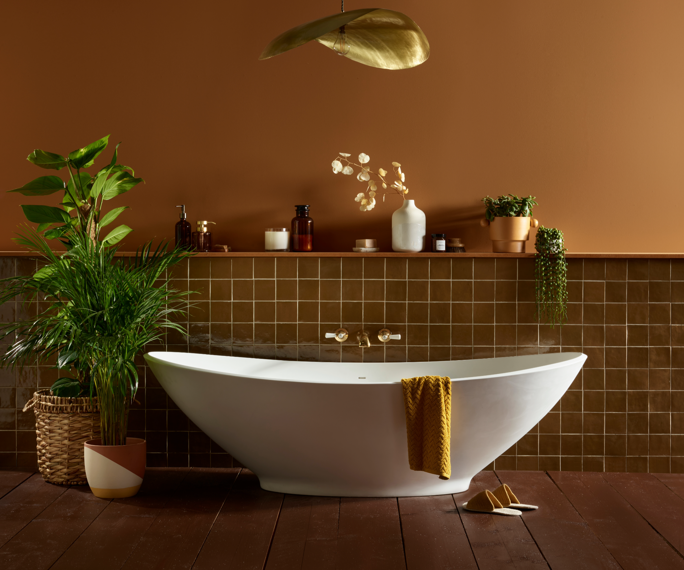 Dark bathroom idea with half tiled half painted brown wall behind a freestanding bath